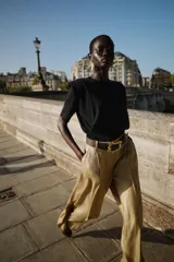 Top negro de tejido de punto, cuello redondo, manga corta y hombreras marcadas. Presenta un bajo ancho y ajustado.