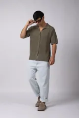 Camisa negra tejida de manga corta, con calado aireado, cuello tipo bowling y botones al tono. Diseño de corte relajado.