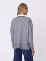 Sweater gris con terminación en lurex y botones decorativos, de corte relajado y mangas largas.