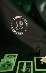 Remera negra de manga corta con cuello redondo y calce oversize. Estampa frontal con diseño de tarot con un león y la leyenda "Tarot x Luxo - La Fuerza".