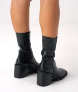 Bota corta color crema con textura de reptil, caña media, punta cuadrada, cierre lateral y taco de madera.