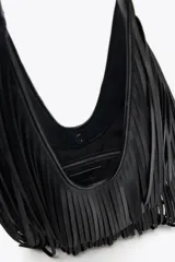 Bolso de hombro negro con flecos en el cuerpo, asa de hombro, bolsillo interior con cremallera y cierre mediante imán.