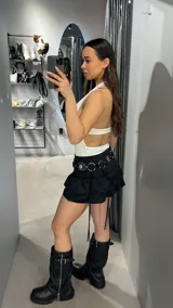 Body blanco con escote halter, abertura en el abdomen con aro metálico y espalda descubierta.