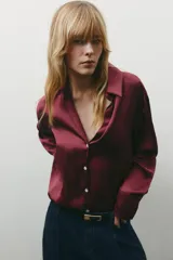 Camisa color borgoña de satén con cuello solapa, escote en pico, manga larga y cierre frontal con botones.