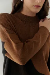 Buzo de punto con diseño geométrico en bloques de color gris y negro, de cuello redondo y mangas largas.