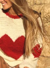 Sweater tejido a mano color crema con cuello redondo y corazón rojo en el frente.
