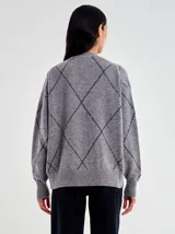 Cardigan de punto gris, corte oversize, con escote en V y botones frontales. Presenta un patrón de rombos formado por líneas de micro lentejuelas negras.