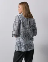 Camisa de mujer estampada con hojas en blanco y negro, cuello con solapa, abertura central con botones, bolsillos aplicados en el delantero y mangas largas con lazo.