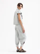 Pantalón de cuero ovino color gris claro, con frunces en el puño de la botamanga que aportan volumen. Tiene cintura doble con pespunte y botones forrados en cuero.