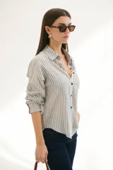 Camisa a rayas verticales color beige y blanco, con cuello clásico, botones marrones y mangas largas.