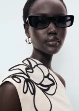 Top de algodón color crema, con cuello asimétrico, detalle de bordado floral en el hombro y frunces laterales. Cierre lateral con cremallera.