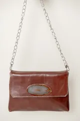 Cartera sobre negra de cuero vacuno con solapa y aplique de piedra ágata. Tiene cadena desmontable plateada.