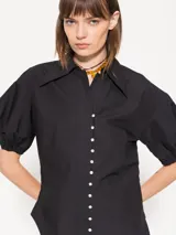 Camisa negra de popelina, de silueta amplia y diseño liviano. Incluye cuello clásico y cierre frontal con botones.