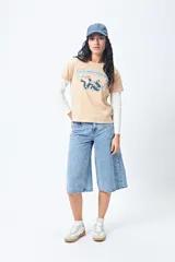 Remera color beige de manga corta con cuello redondo y estampado con ilustración gráfica al frente y frase retro.