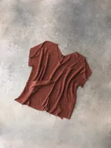 Poncho escotado color ladrillo, de tejido de punto con hilado italiano. Presenta tajos laterales y tajo frontal.