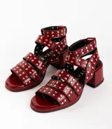 Sandalias de cuero color bordó con tres tiras horizontales sobre el empeine y pulsera al tobillo, ambas con apliques de tachas plateadas.