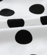 Vestido midi blanco con lunares negros, de corte suelto, cuello redondo y mangas cortas.