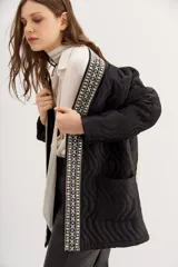 Saco negro acolchado con diseño de ondas y ribete bordado con cuentas.