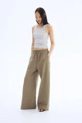 Pantalón de corte holgado color arena, confeccionado en tejido liviano de mezcla de lino. Modelo de tiro alto con elástico revestido en la cintura, cordón para ajustar fino y piernas amplias con bolsillos al bies.