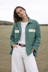 Chaqueta verde con apliques dorados en los bolsillos y cierre frontal con botones.