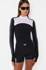 Top deportivo negro de tricot con recortes pisados con bordador, media polera, manga larga con mitones y estampa en lateral del frente y espalda.