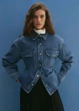 Campera de jean azul con cuello camisero, cierre frontal con botones metálicos, dos bolsillos con solapa abotonada en el pecho y mangas largas con puños abotonados.