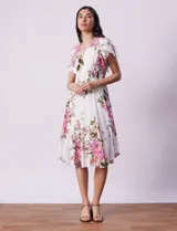 Vestido blanco con estampado floral en tonos rosados, violetas y verdes. Escote en V tanto en la parte delantera como en la espalda. Cintura elastizada con punto smock y forro interno a tono.