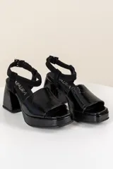 Sandalias negras de cuero con plataforma y taco cuadrado. Tiras anchas sobre el empeine y pulsera al tobillo con hebilla.