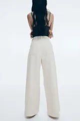 Pantalón de jean color crema, de corte amplio y cintura alta, con detalle de trenzado en la pretina.