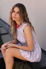 Vestido corto a rayas verticales de colores naranja, verde y azul, con escote redondo y elástico en el torso hasta la cadera.