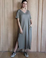 Vestido midi verde oliva de corte recto, con cuello en V, mangas cortas y bolsillos laterales. Presenta aberturas laterales en el ruedo.