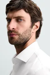 Camisa blanca de manga larga con cuello italiano abierto y puños abotonados. Presenta un corte slim fit y cierre frontal de botonadura.