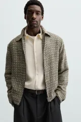 Sobrecamisa de hombre regular fit confeccionada en tejido con estructura irregular en tonos beige, marrón y negro. Tiene cuello solapa, manga larga con puños abotonados, bolsillos laterales y cierre frontal con cremallera.