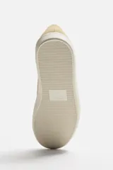 Zapatillas bajas color beige de gamuza, con cordones y suela blanca.