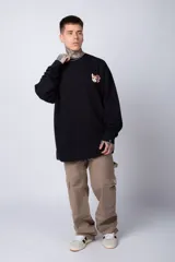 Buzo color crema de corte oversize confeccionado en tela friza con cuello redondo y puños y cintura acanalados. Presenta un pequeño bordado en el frente y un estampado grande en la espalda.