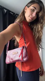 Cartera mini tipo baguette color bordó, confeccionada en cuero. Tiene correa de hombro fina y un bolsillo interno con cierre.