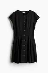 Vestido corto negro de algodón con escote redondo, manga japonesa, botonadura frontal y cintura entallada con pinzas. Falda acampanada con inserciones para dar volumen.