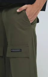 Pantalón cargo verde militar de corte recto y tiro alto, con bolsillos laterales con solapa y etiqueta con logo en la pierna.