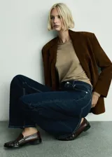 Pantalón de jean azul oscuro, de corte flare y tiro alto, con cinco bolsillos y trabillas para cinturón.