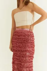 Pollera larga de fiesta color rosado con textura de flecos, calce recto y cintura alta.