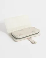 Billetera de cuerina color crema con estampado de flores y cierre con broche a presión.