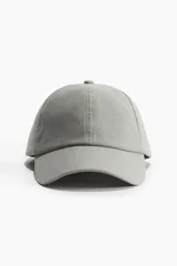 Gorra gris de lino y algodón con ojales bordados en la parte superior y trabilla ajustable con hebilla de metal atrás.