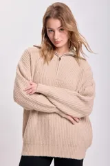 Sweater beige de punto grueso, con cuello polo y cierre metálico parcial.