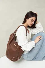 Bolso shopper negro de símil cuero texturizado con asas de hombro y detalles de tachas metálicas.