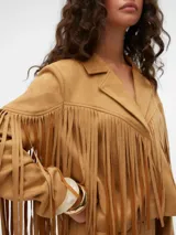 Chaqueta corta color camel con flecos en mangas y pecho, cuello clásico y cierre frontal con broches.