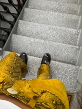 Pantalón acampanado de cuero sintético con estampado de piel de serpiente en tonos azules.