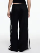 Pantalón de lino negro con elástico en la cintura, tiro medio y calce relajado. Lleva tiras en color gris aplicadas a los laterales, que quedan sueltas en la parte inferior y pueden anudarse.