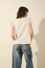 Remera blanca de algodón con mangas cortas con volados de encaje y detalle de volado vertical en el frente.