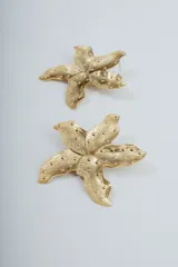 Aros colgantes con forma de estrella de mar dorada con textura irregular.