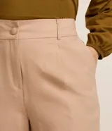 Pantalón de corte ancho confeccionado en sastrería de viscosa color beige, con cintura alta, trabillas, cierre con botón forrado y bolsillos laterales.